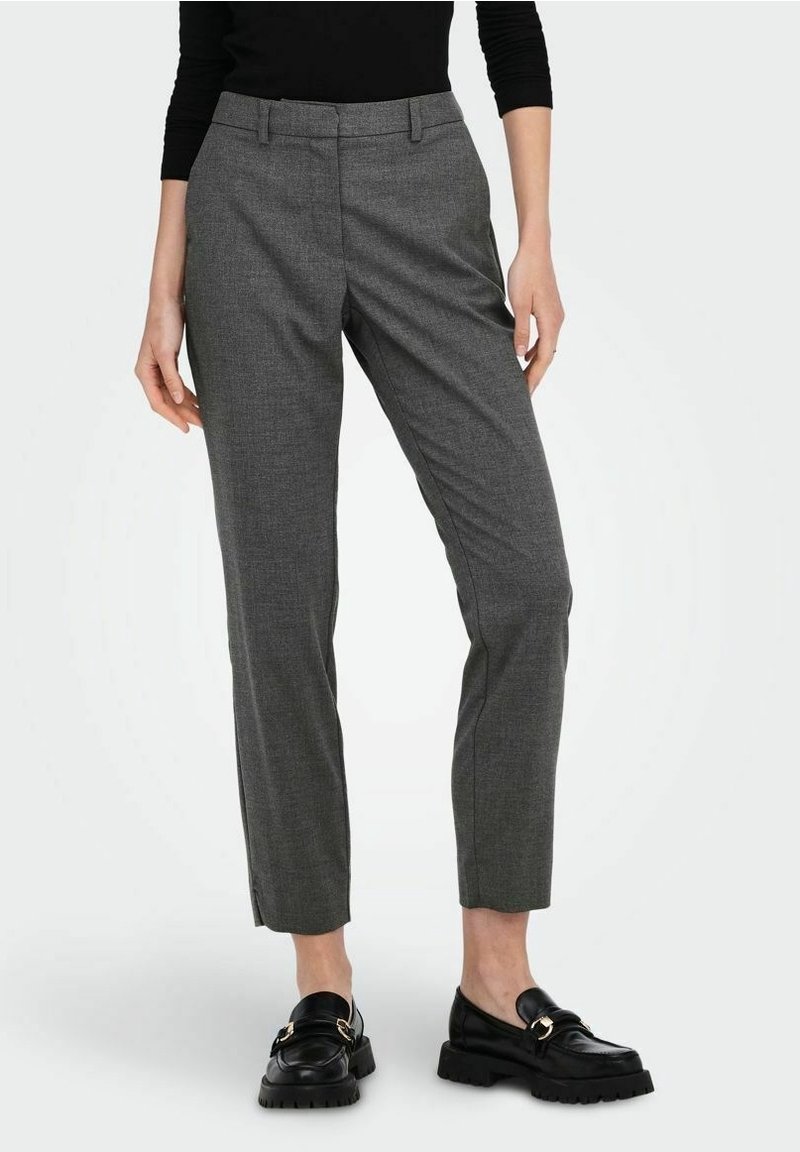Pantaloni grigi su misura in un tessuto testurizzato, con una vestibilità slim e una leggera affusolatura alla caviglia, abbinati a mocassini neri con accenti dorati.