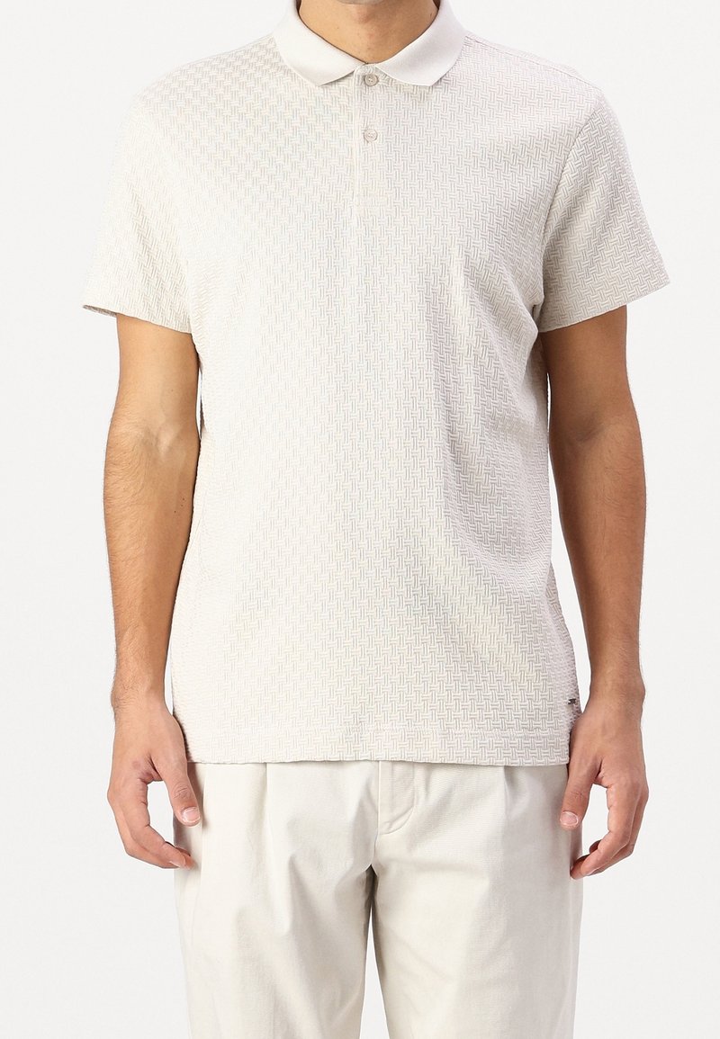 Polo beige à manches courtes avec un motif géométrique texturé, doté d'un col classique et de trois boutons sur la patte de boutonnage.