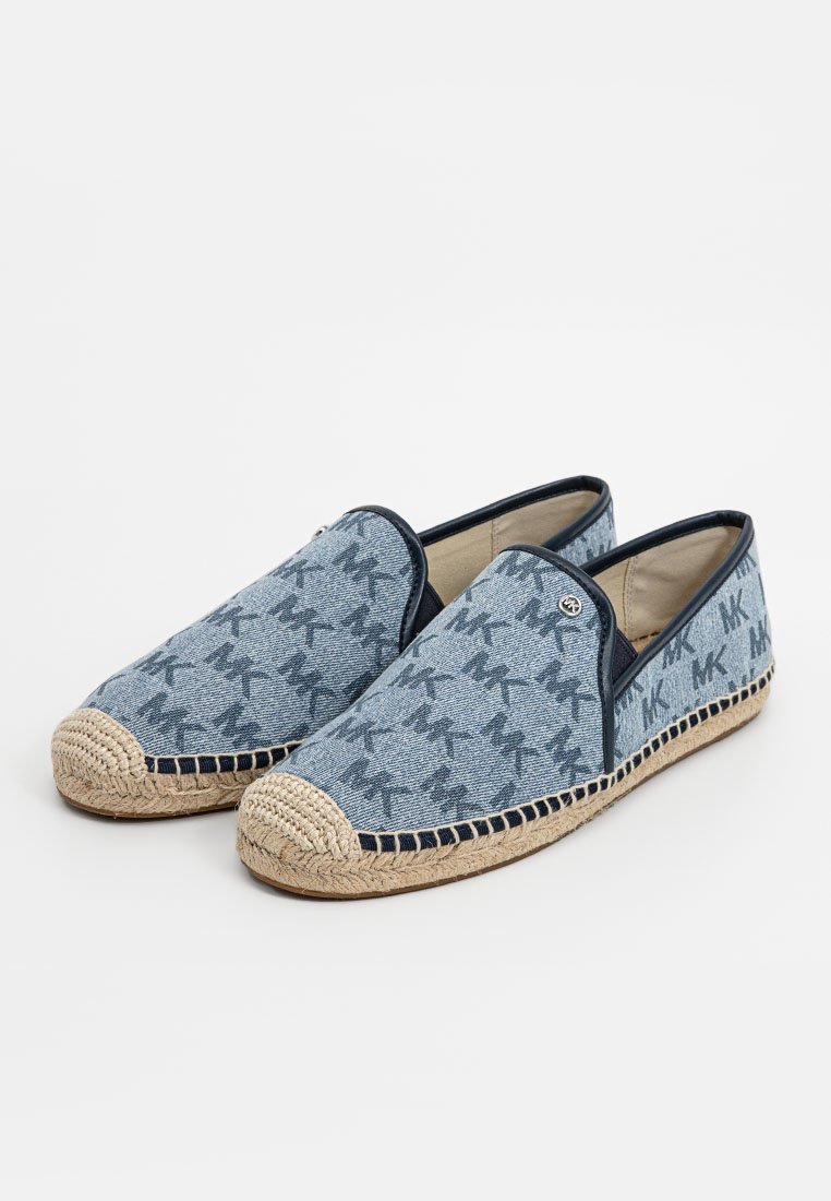 Chaussures en denim à enfiler avec une semelle en jute tissé, présentant un motif bleu et un liseré bleu marine. Bout arrondi avec un bord cousu et tressé.