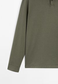 Olijfgroene polo met lange mouwen, gemaakt van zachte katoen, met een knoopsluiting met twee knopen en gestikte manchetten voor een comfortabele pasvorm.