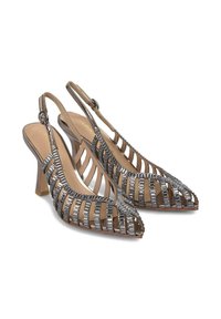 Escarpins à talons hauts avec des sangles métalliques décoratives, bouts pointus et un talon transparent. Dispose d'une semelle intérieure beige avec le nom de la marque.
