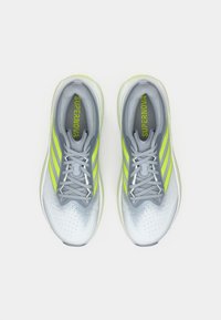 Szare buty do biegania o gładkim wykończeniu, ozdobione neonowożółtymi paskami i sznurówkami, z oddychającą siateczkową cholewką i wyściełanym kołnierzem.