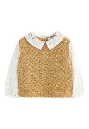 Beige ærmeløs strikvest over hvid langærmet bluse med blomster-øjer og bølget krave med udskæringsdesign.