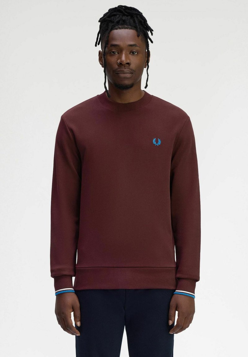 Felpa bordeaux con collo a giro e polsini e orlo ribbed. Presenta un logo blu sul petto e dettagli a righe sui polsini. Texture liscia.