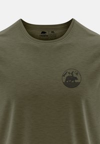 Olivgrünes T-Shirt mit Rundhalsausschnitt, aus weichem Stoff gefertigt. Mit einem schwarzen geometrischen Bären-Design innerhalb eines kreisförmigen Motivs auf der Brust.