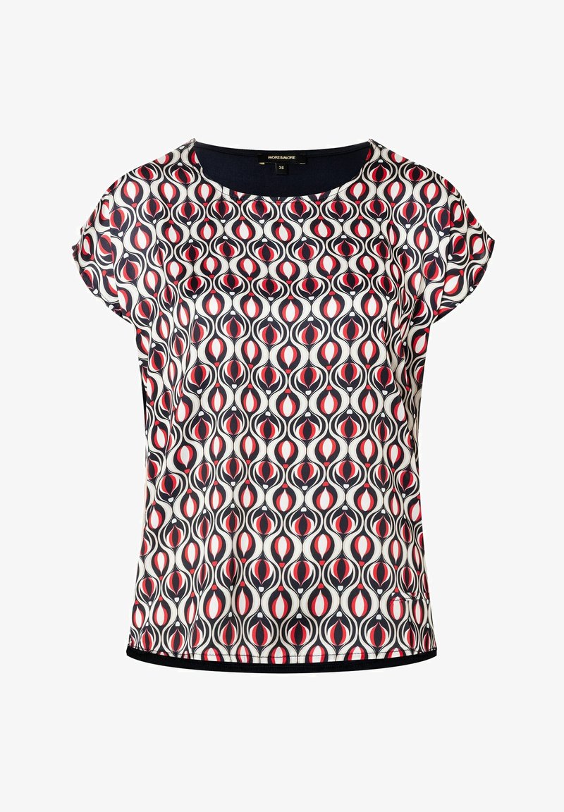 Blusa de manga corta en una tela ligera y brillante con un patrón simétrico rojo y negro sobre fondo blanco. Ribete de contraste en el cuello.