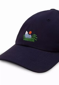 Granatowa czapka z tkaniny z haftowanym z przodu wzorem gór, drzew i słońca w zielonych, białych i pomarańczowych kolorach.