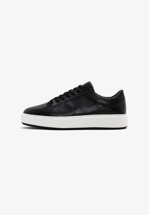 Black leather sneaker with a smooth finish, rounded toe, flat white rubber sole, and black laces featuring seven eyelets.