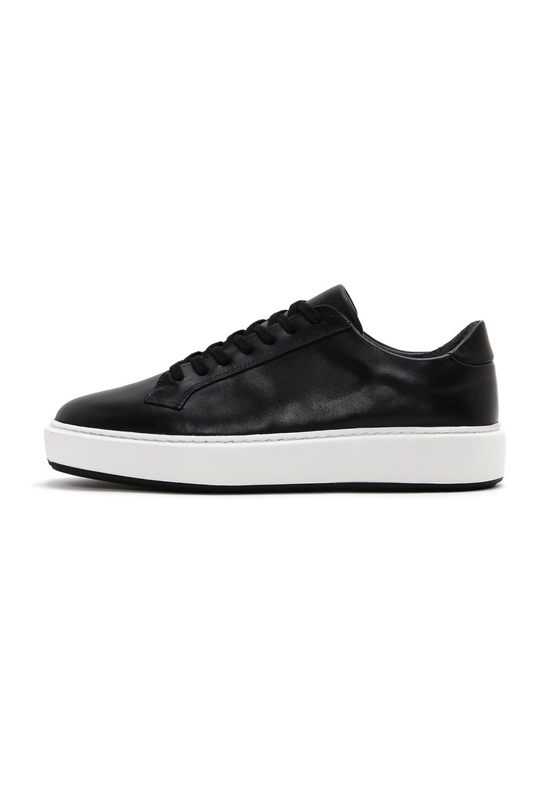 Baskets en cuir noir avec une finition lisse, bout rond, semelle plate en caoutchouc blanc et lacets noirs comportant sept œillets.