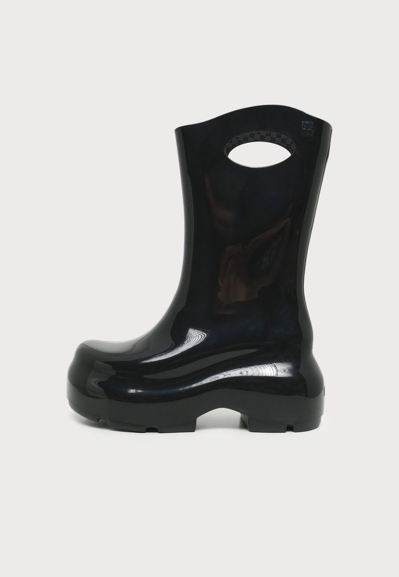 Botte de pluie en caoutchouc noir brillant avec un bout arrondi, une semelle épaisse et une poignée ovale découpée près du haut pour faciliter l'enfilage.