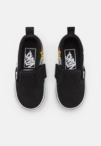 Svarta canvas slip-on skor med elastiska sidodetaljer, vita gummisulor och flerfärgade grafiska detaljer på hälarna.