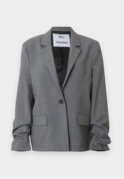Γκρι σακάκι με ένα κουμπί, με επάλληλο πέτο, δύο τσέπες με καπάκι και ελαφρώς ρυτιδωμένα μακριά μανίκια, με ετικέτα "Won Hundred" στην εσωτερική γιακά.