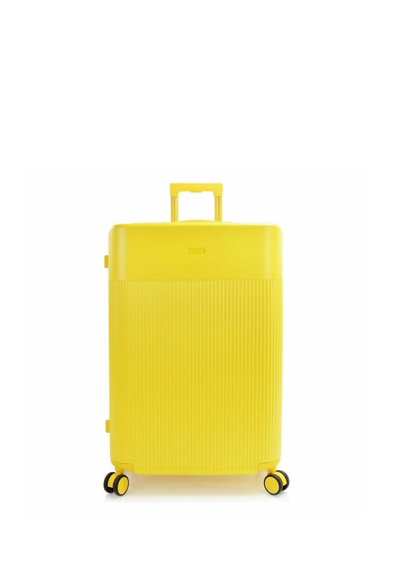 Valise rigide jaune vif avec moitié inférieure texturée, quatre roues doubles et poignée télescopique étendue.