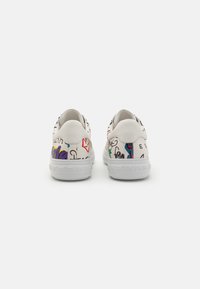 White sneakers with vibrant graffiti-style patterns, featuring a sleek design, textured leather upper, and white rubber sole with branding.