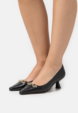 Escarpins en cuir noir à bout pointu avec un petit talon carré. Dotés d'un détail chaîne dorée sur l'avant. Texture lisse et design épuré.
