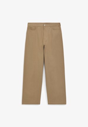 Beige weit geschnittene Hose aus Baumwolle, mit einer Vorderknopfschließe, zwei Fronttaschen und einer sauberen, strukturierten Oberfläche.