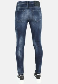 Skinny jeans van donkerblauwe denim met een gladde textuur, voorzien van een klassieke vijf-pocket ontwerp en een zwart merklabel op de tailleband.