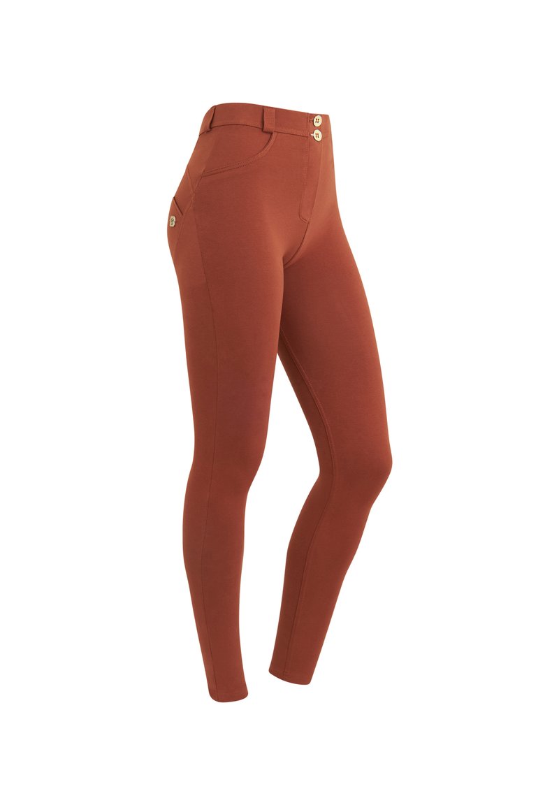 Leggings color ruggine con una texture liscia, caratterizzati da un alto elastico in vita e due bottoni frontali. Dettaglio della tasca laterale visibile.