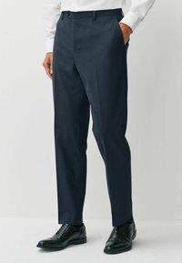 Dark navy dress pants with a textured finish, featuring a straight leg design, side pockets, and waistband with belt loops. Pairing black shoes.
