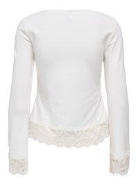 Haut blanc à manches longues avec bordure en dentelle aux poignets et à l'ourlet, vu de dos.