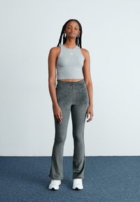 Gray ribbed crop top and gray flared pants, both fitted, with a smooth texture. Worn with white athletic shoes. Simple design, minimal detailing.