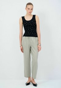 Svart linne med vita prickar, kombinerat med ljusgrå, löst sittande byxor. Modellen bär svarta ballerinas, och accessoarerna inkluderar silverarmband.