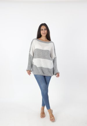 Lichte, gebreide trui met horizontale grijs-witte strepen. Ontspannen pasvorm, brede bootnek en verlaagde schouders. Gekleed met blauwe jeans.