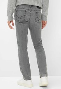 Grijze jeans van denim met een slim fit, vijf zakken en gestikte accenten, gecombineerd met witte sneakers en een gestructureerd grijs sweater.