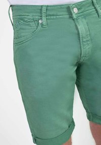 Groene katoenen shorts met een klassieke pasvorm, voorzien van een opgerolde zoom, een vijf-pocket ontwerp en een metalen knoopsluiting. Gladde textuur en matte afwerking.