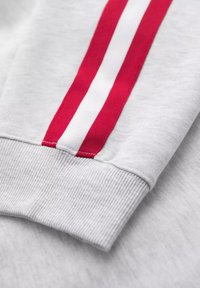 Grauer Sweatshirtbund mit zwei roten und einem weißen vertikalen Streifen entlang der Kante, aus weichem Baumwollmaterial gefertigt.