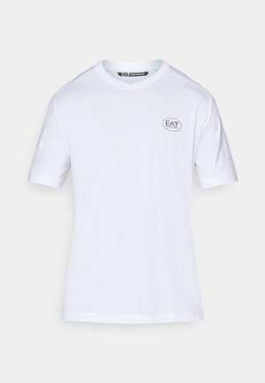 Biała, krótko rękawowa koszulka z bawełny. Posiada małe, okrągłe czarne logo po lewej stronie klatki piersiowej oraz klasyczny okrągły dekolt.