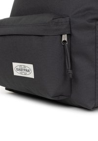 Svart Eastpak ryggsäck med en slät yta, en framficka med dragkedja och en logotyp på sidan.
