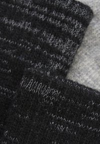 Schwarzer und grauer Strickstoff mit gestreiftem Muster und strukturiertem Finish, das eine weiche Wollähnliche Optik und ein dickes, warmes Gefühl bietet.