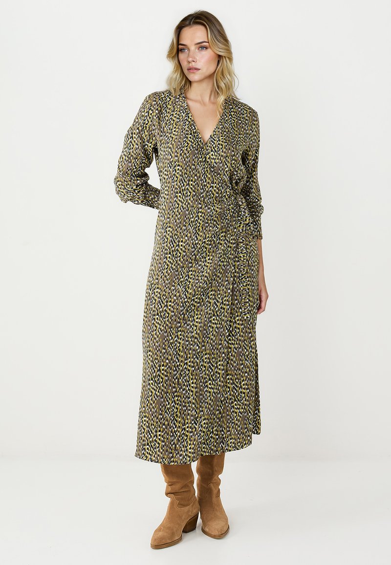 Robe longue style portefeuille avec motif marron et jaune ; manches longues et encolure en V. Portée avec des bottes hautes jusqu'aux genoux couleur camel pour contraster.