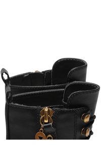 Stivaletti neri in pelle con hardware dorato, cerniere e dettagli. Il design include cuciture decorative e estremità ad anello per i lacci.