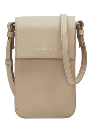 Beige leather crossbody bag with a flap, adjustable strap, and gold logo on the front. Smooth texture and minimalist design.