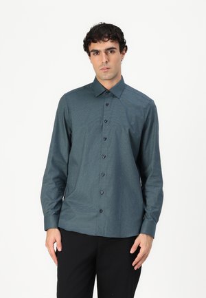 Dark teal button-up shirt in a textured fabric, featuring a pointed collar, long sleeves, and black buttons. Worn with black trousers.