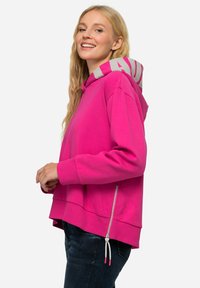 Felpa rosa brillante con cappuccio a righe grigie, tasca laterale con zip e polsini a coste. Vestibilità casual e texture del tessuto morbida.