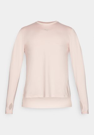 Długi rękaw sportowy t-shirt w jasnoróżowym kolorze, wykonany z gładkiego materiału; posiada otwory na kciuki oraz odblaskowy akcent logo na klatce piersiowej.