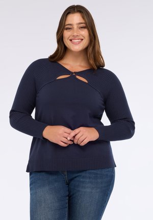 Granatowy sweter z dzianiny z prążkowanymi długimi rękawami, okrągłym dekoltem i detalem w kształcie dziurki na wysokości klatki piersiowej. Miękka faktura, luźny krój i jednolity kolor.