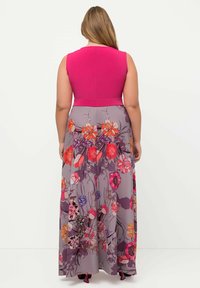 Maxiklänning med en åtsittande rosa överdel och en utsvängd kjol dekorerad med ett blommönster i livfulla färger på en grå bakgrund.