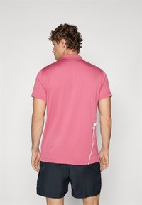 Polo de mangas curtas em tecido rosa com uma textura suave. Apresenta uma discreta risca lateral branca e um design de colarinho clássico. Vista traseira mostrada.