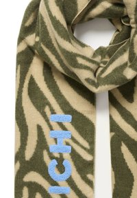 Sciarpa a maglia con un motivo a zebra beige e verde, con lettering ricamato blu chiaro. Texture morbida e forma rettangolare allungata.