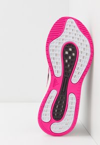 Sole adidas boty s růžovým gumovým okrajem, bílými a černými texturovanými vzory a mřížkovým designem pro trakci a flexibilitu.