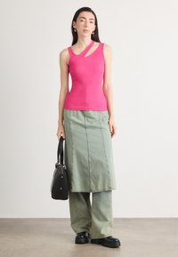 Tettsittende rosa ribbet tanktopp med asymmetrisk stroppedesign, kombinert med et grønt denim maxiskjørt og svarte blokkhæl sko.