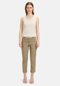 Beige mouwloos topje met ronde halslijn, gecombineerd met lichtkhaki taps toelopende broek. Witte riem voegt contrast toe. Minimale details, gladde textuur.