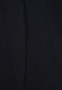 Gros plan sur un tissu noir avec une texture fine de tricot visible et une couture centrale verticale.
