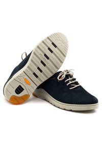Zapatos de ante azul marino con cordones y suelas de goma beige. Características incluyen acentos naranjas y un upper texturizado con detalles de costura visibles.
