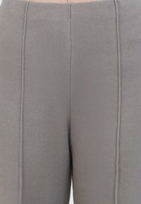Leggings grigi a coste con dettagli di cucitura verticale. Vita elasticizzata per maggiore comfort, con una texture morbida e design aderente.