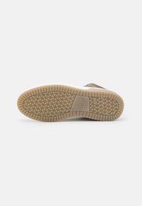 Des chaussures avec une semelle extérieure en caoutchouc à motif texturé, de couleur brun clair, et une semelle intermédiaire blanche, affichant la marque Gabor.